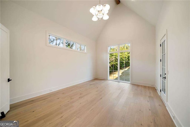 spare room with a notable chandelier, baseboards, high vaulted ceiling, and wood finished floors