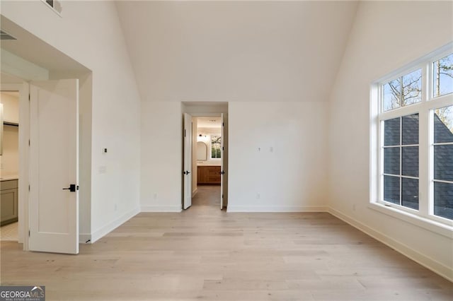 unfurnished bedroom with vaulted ceiling, visible vents, and light wood-type flooring