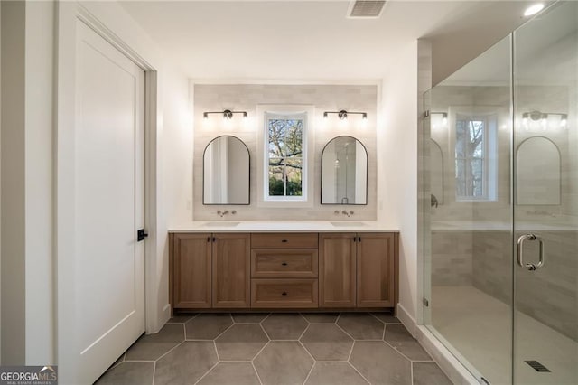 bathroom featuring double vanity, a stall shower, visible vents, and a sink