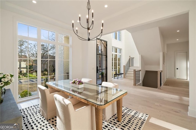 dining area with stairway, light wood finished floors, a wealth of natural light, and a chandelier