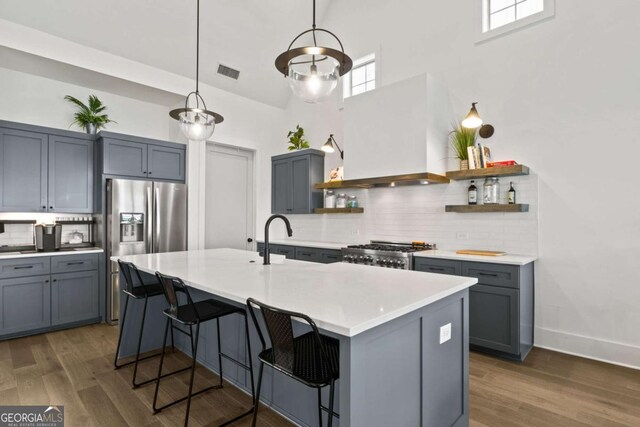 kitchen with visible vents, open shelves, stove, wall chimney exhaust hood, and a sink