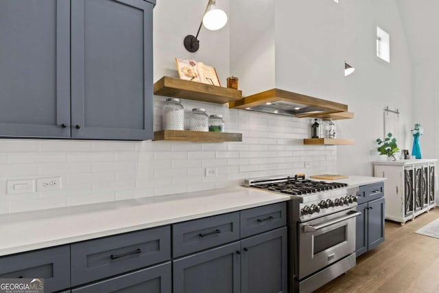 kitchen with open shelves, stainless steel range, wood finished floors, and premium range hood