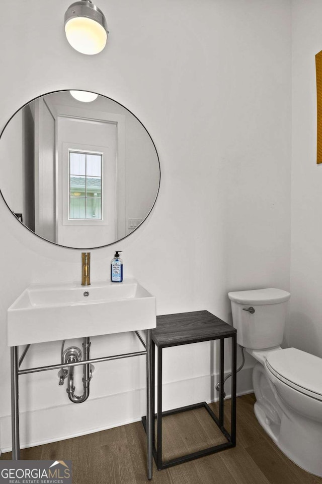 bathroom featuring toilet, baseboards, and wood finished floors