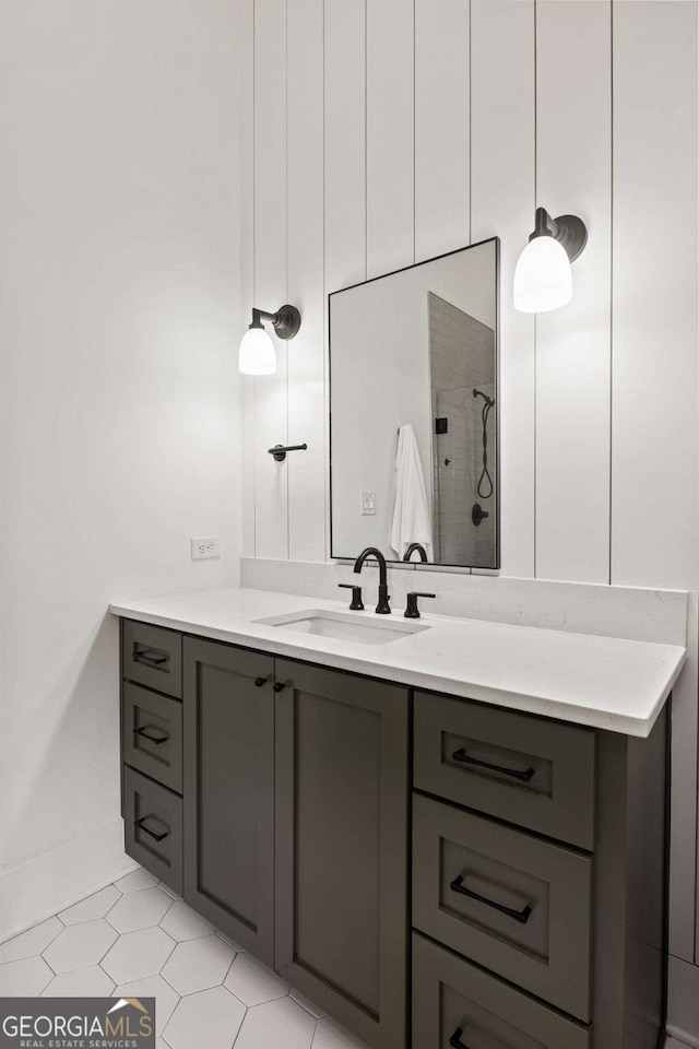 full bath featuring vanity, tile patterned flooring, and a tile shower