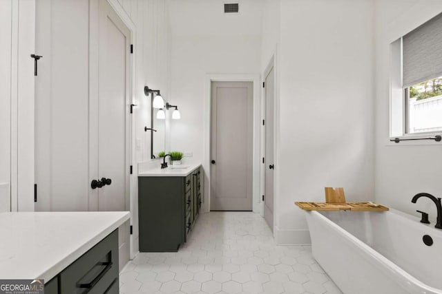 full bath with vanity, a soaking tub, and visible vents