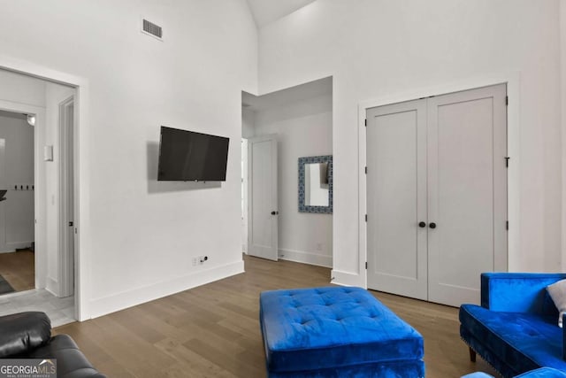 living area featuring visible vents, high vaulted ceiling, baseboards, and wood finished floors