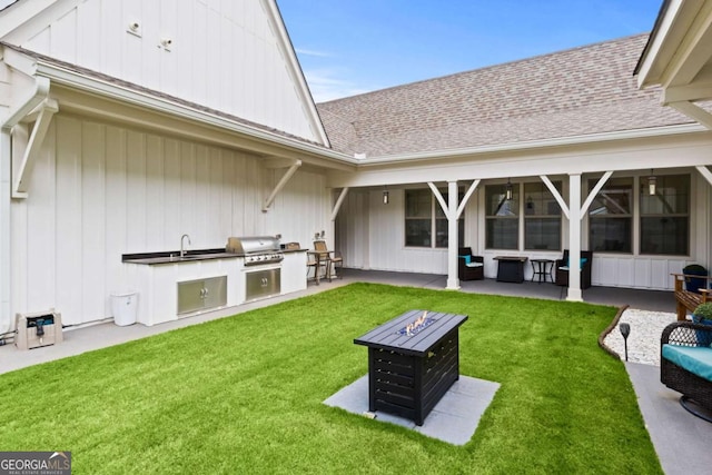 view of yard with a sink, a patio area, exterior kitchen, and an outdoor fire pit