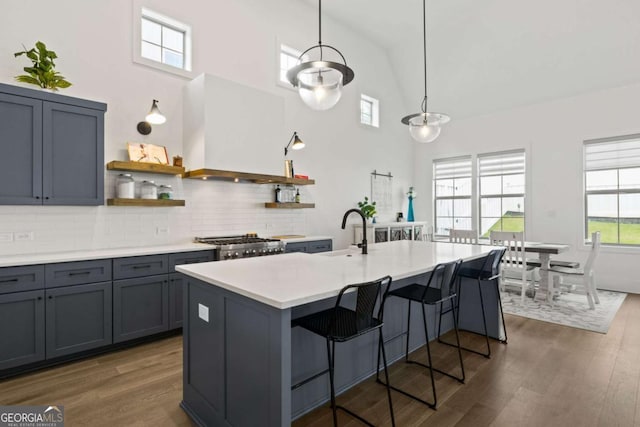 kitchen with a sink, open shelves, light countertops, custom range hood, and dark wood-style flooring