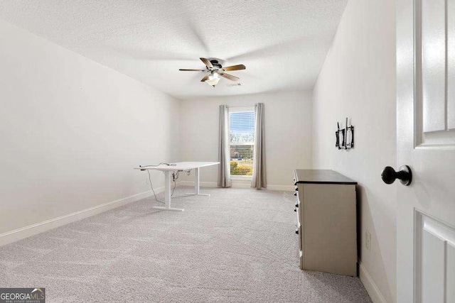 interior space featuring light carpet, baseboards, a textured ceiling, and ceiling fan