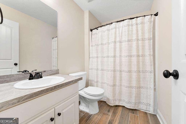 full bathroom with curtained shower, toilet, vanity, wood finished floors, and a textured ceiling