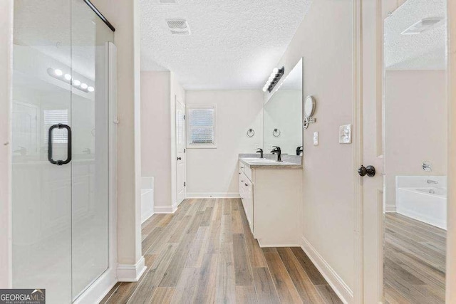 bathroom featuring visible vents, a textured ceiling, a garden tub, and wood finished floors