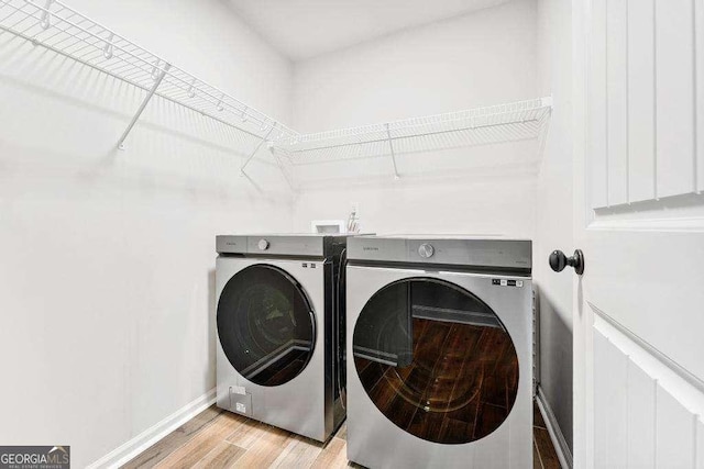 clothes washing area featuring light wood-style floors, baseboards, separate washer and dryer, and laundry area