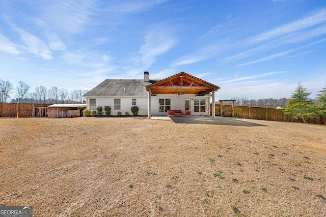 rear view of house with a fenced backyard, a yard, a chimney, and a patio