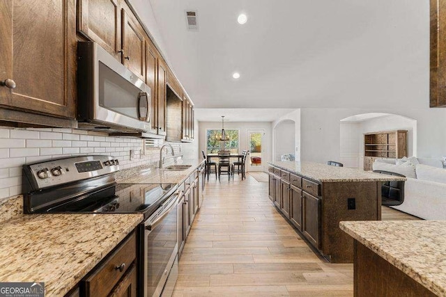 kitchen with visible vents, backsplash, light wood-type flooring, stainless steel appliances, and a sink