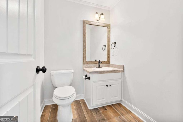 half bath with toilet, vanity, baseboards, and wood finished floors