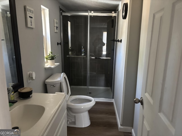 bathroom with a stall shower, toilet, vanity, and wood finished floors