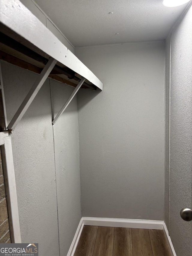 walk in closet with dark wood-type flooring