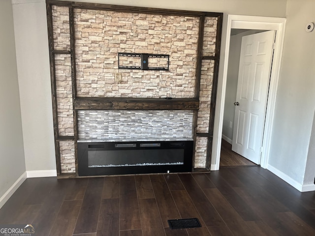 interior details with a glass covered fireplace, baseboards, and wood finished floors