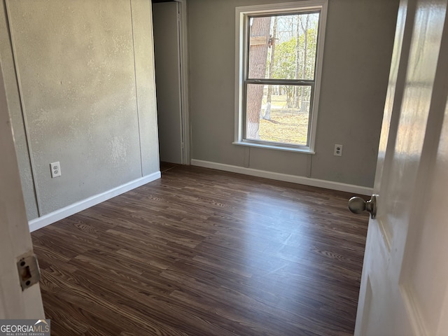 unfurnished room featuring baseboards, a healthy amount of sunlight, and dark wood-style floors