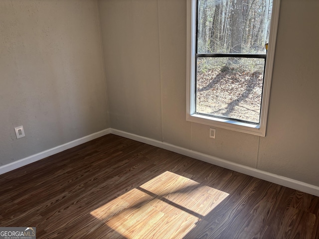 empty room featuring baseboards and dark wood-style flooring