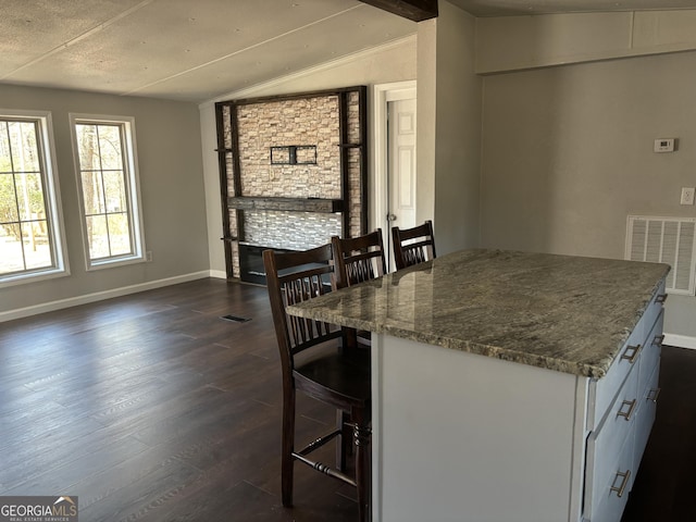 unfurnished dining area featuring vaulted ceiling, baseboards, visible vents, and dark wood-type flooring