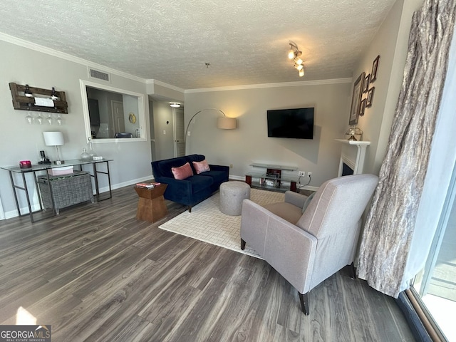 living area with visible vents, dark wood-type flooring, baseboards, ornamental molding, and a textured ceiling