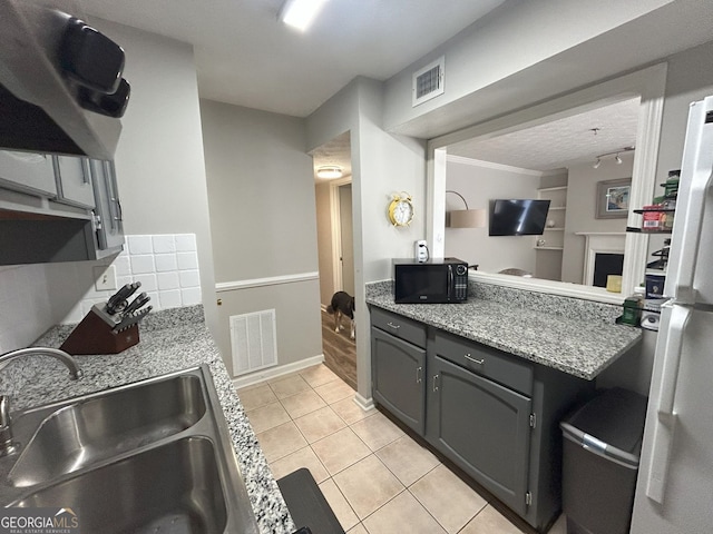 kitchen featuring light tile patterned floors, visible vents, black microwave, and a sink