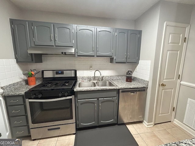 kitchen featuring under cabinet range hood, gray cabinetry, appliances with stainless steel finishes, and a sink