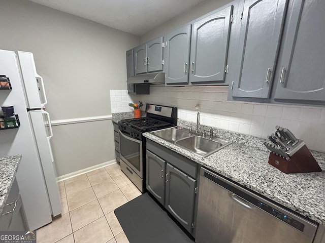 kitchen with light tile patterned flooring, a sink, decorative backsplash, under cabinet range hood, and appliances with stainless steel finishes