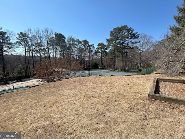 view of yard with a tennis court and fence