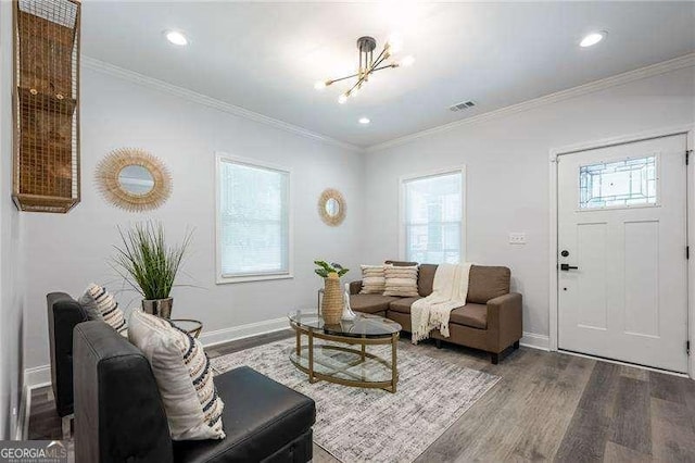 living area featuring baseboards, wood finished floors, visible vents, and ornamental molding