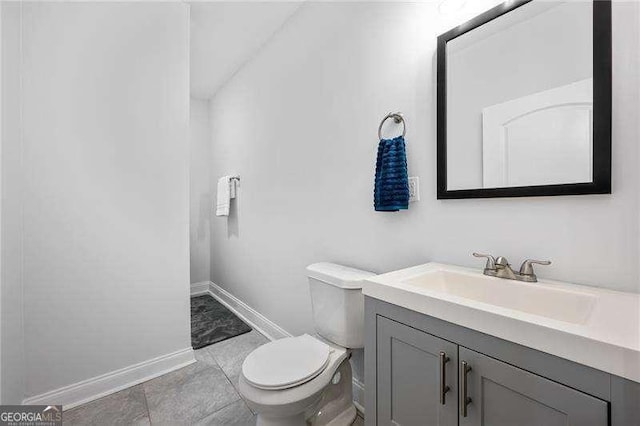 bathroom with toilet, vanity, and baseboards