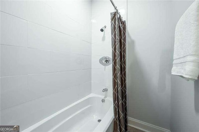 full bath featuring baseboards and shower / bath combination with curtain