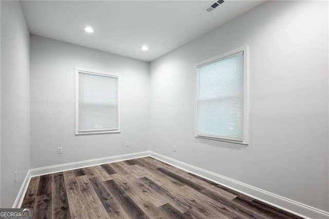 spare room with dark wood-type flooring, recessed lighting, baseboards, and visible vents