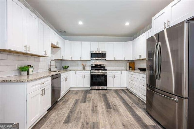 kitchen featuring light stone counters, a sink, decorative backsplash, dark wood-type flooring, and stainless steel appliances