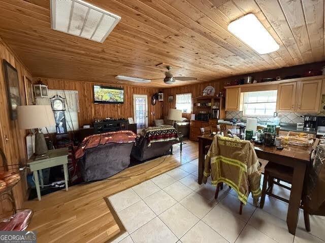 dining area featuring wooden walls, wooden ceiling, light wood-style floors, and ceiling fan