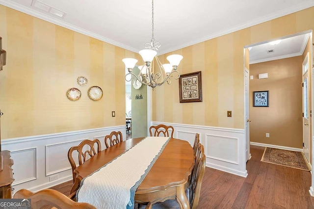 dining area with a wainscoted wall, wood finished floors, a notable chandelier, and crown molding