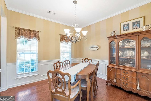 dining area featuring dark wood finished floors, an inviting chandelier, a wainscoted wall, and visible vents