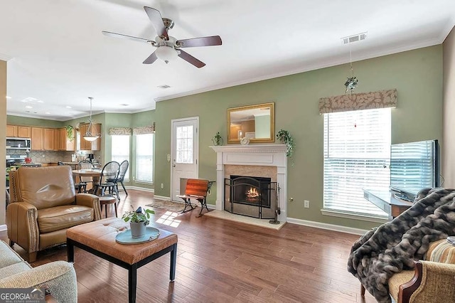 living area featuring ceiling fan, baseboards, ornamental molding, and visible vents