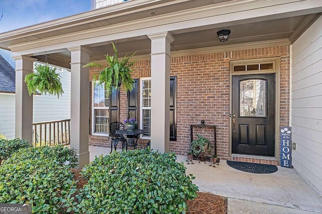doorway to property with brick siding and covered porch