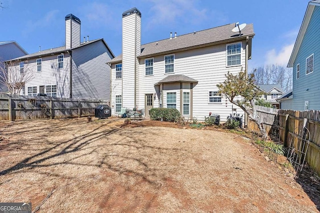 back of property with a fenced backyard and a chimney