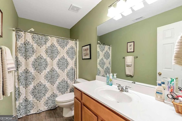 bathroom featuring toilet, vanity, wood finished floors, and visible vents