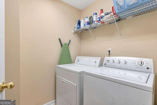 clothes washing area featuring washing machine and dryer, baseboards, and laundry area