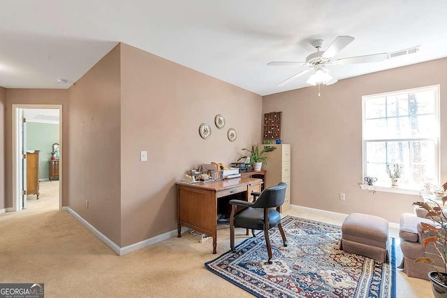 office space featuring a ceiling fan, baseboards, and light carpet