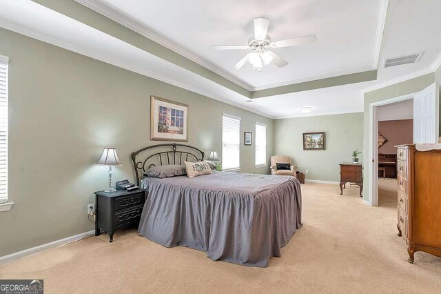 bedroom with ornamental molding, visible vents, light colored carpet, and a tray ceiling