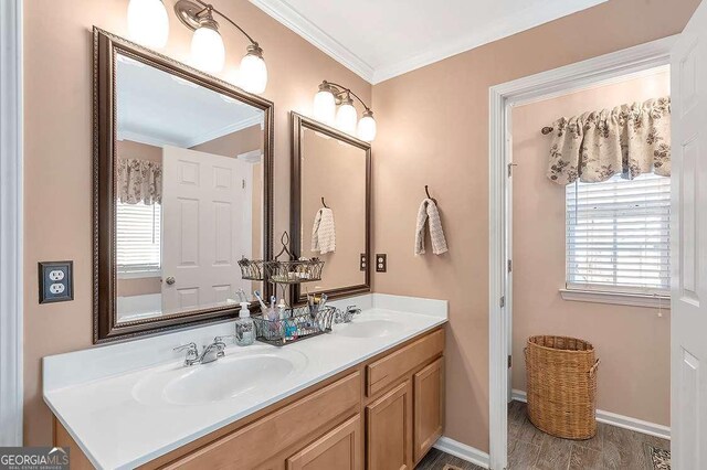 bathroom featuring wood finished floors, visible vents, a sink, and ornamental molding
