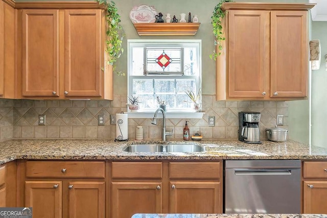 kitchen featuring stainless steel dishwasher, light stone counters, a sink, decorative backsplash, and brown cabinets