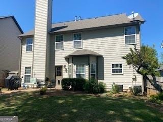 rear view of property with fence, a lawn, and a chimney