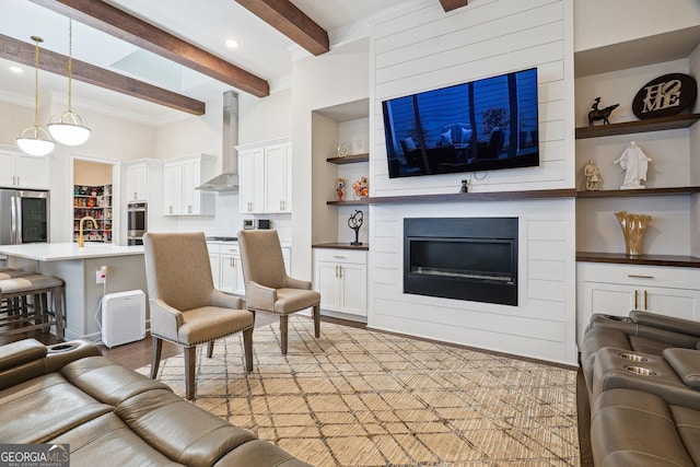 living room featuring built in features, ornamental molding, beam ceiling, light wood-style flooring, and a fireplace