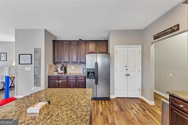 kitchen featuring tasteful backsplash, baseboards, light stone countertops, stainless steel fridge with ice dispenser, and wood finished floors